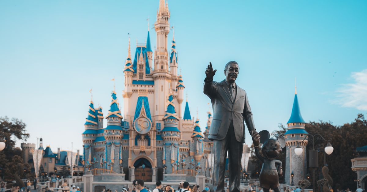 View of the iconic Cinderella Castle at Walt Disney World in Orlando, Florida, with crowd and statue.